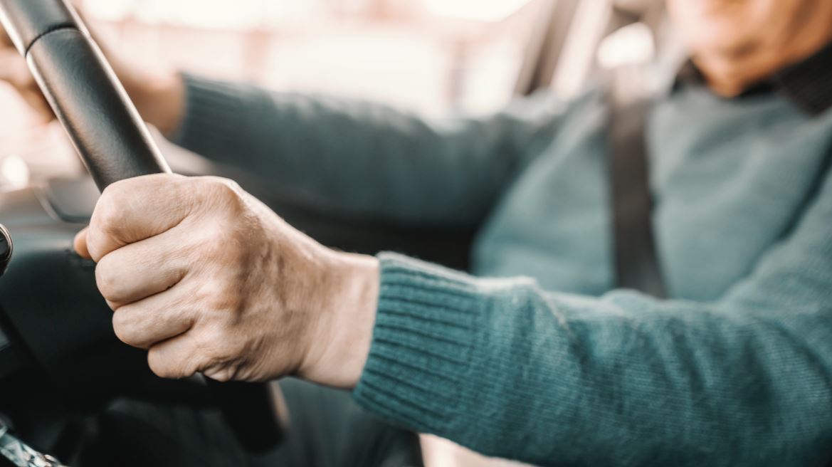 Elderly man's hands on steering wheel