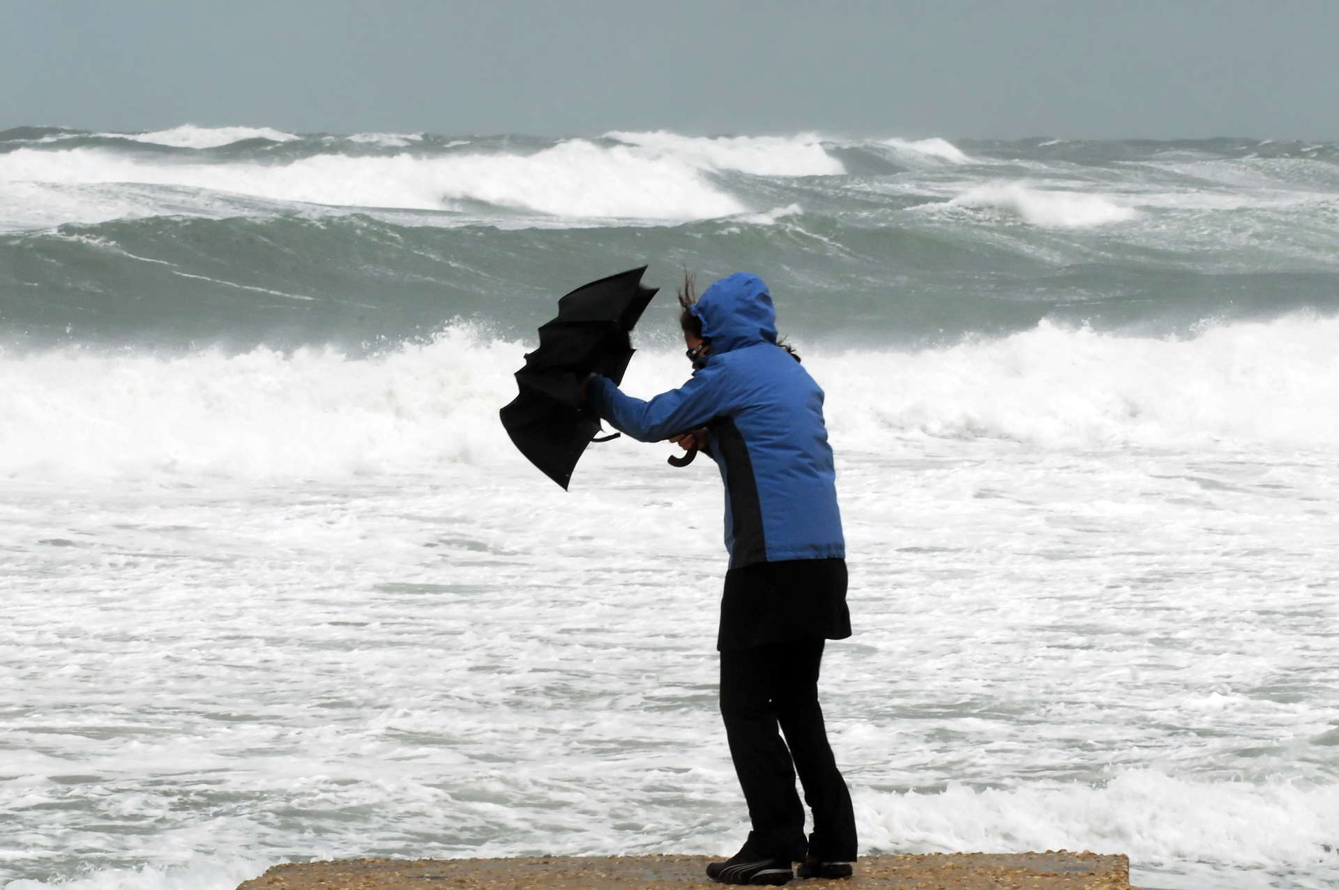 Person on beach with umbrella being blown in the wind