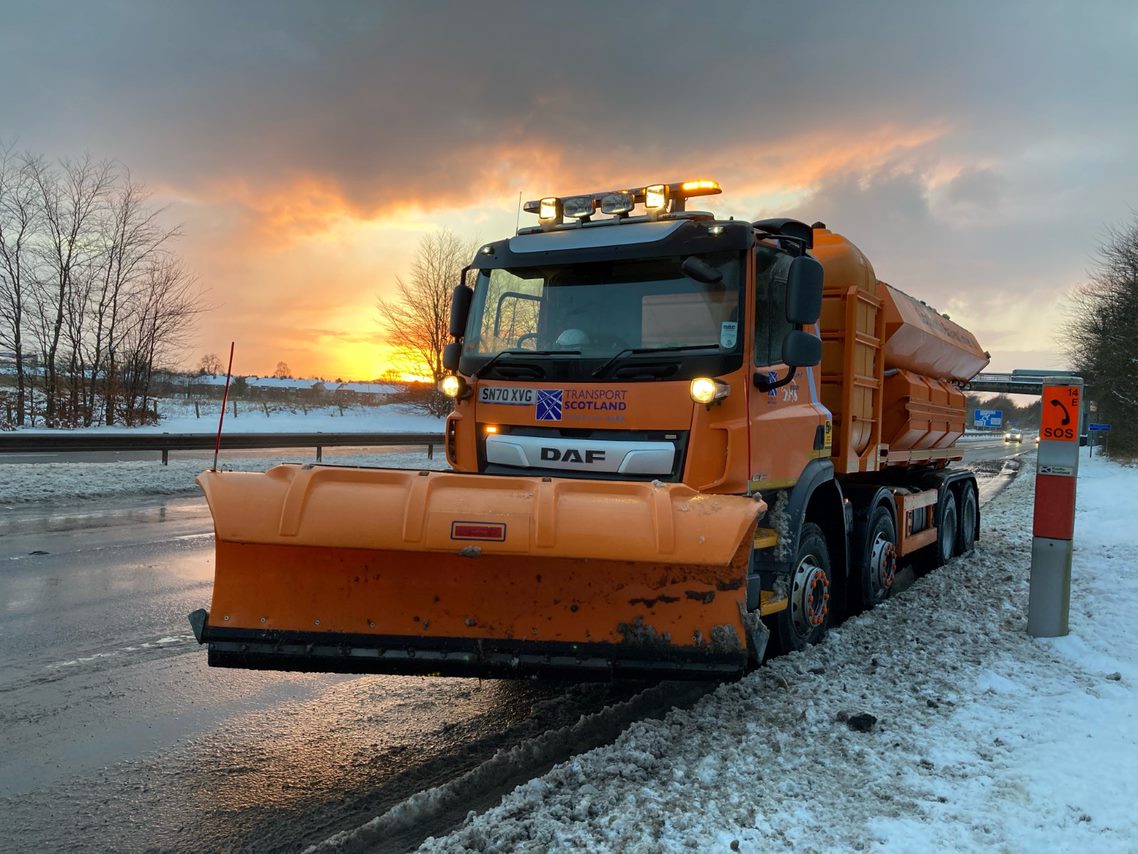 Orange gritter on a snowy road